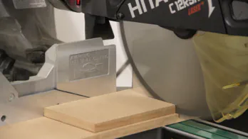 A miter saw is used to cut a piece of MDF.