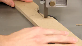 A band saw is used to cut a notch in a piece of MDF.