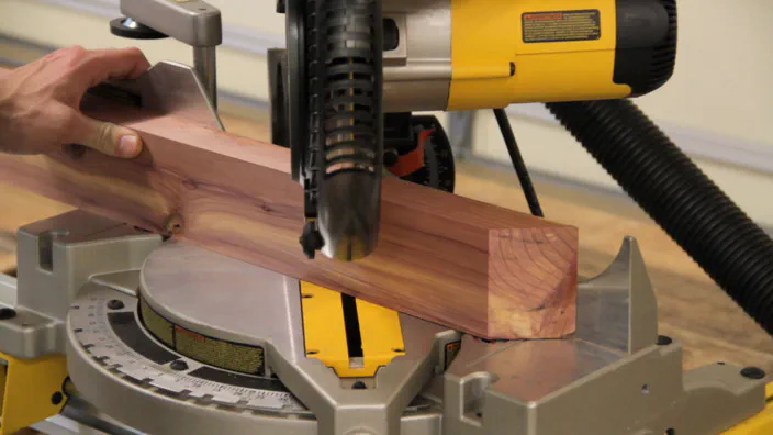 A miter saw is used to cut a cedar board into separate parts.