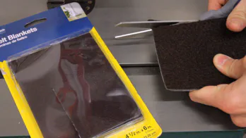 Scissors are used to cut a piece of felt pad.