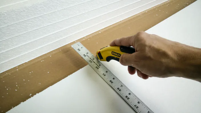 Scoring a piece of garage door insulation with a knife