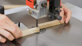 A bandsaw is used to cut a small piece of MDF.