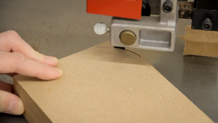 A curve is cut in a piece of MDF using a band saw.