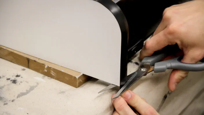 Plastic T-Molding is cut to length with a pair of scissors.
