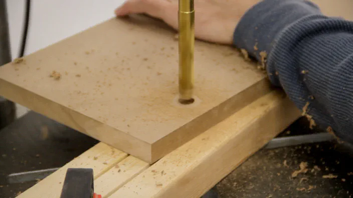 A hole is drilled in a piece of MDF.