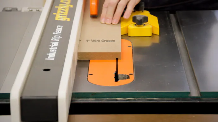 A bevel is cut in a piece of MDF on a table saw.