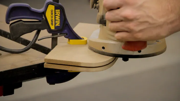 A slot is cut along a curved MDF edge using a router.