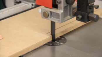 A band saw is used to cut a long notch in a piece of MDF.