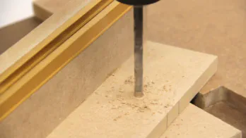 A hole is drilled in the MDF fence.