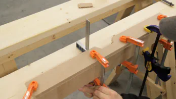 Glue and clamps are used to join two pieces of MDF.