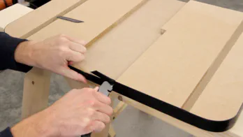 A knife is used to trim off excess plastic T-molding.