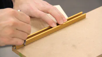 A pencil is used to mark a line on a piece of MDF.