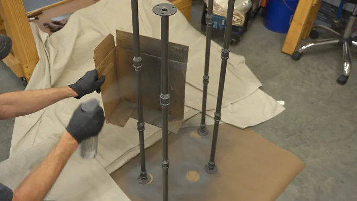Paint is applied to steel pipe legs.