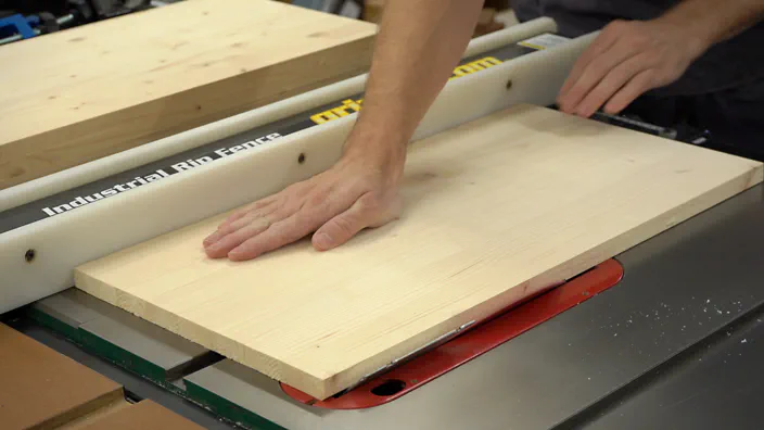 A table saw is used to cut an angle on wooden shelving.