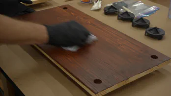 Gel stain is applied to wooden shelving.
