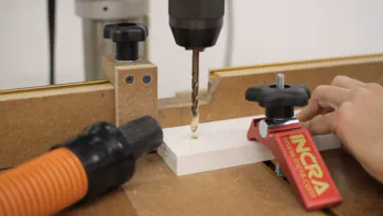 A drill press is used to drill holes in a wooden leg.