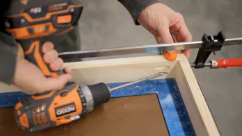 A drill is used to screw two pieces of wood together.