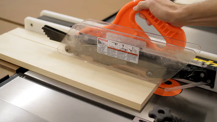 A table saw is used to rip a pine board to width.