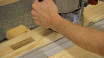 A router cuts a groove in the workbench top.