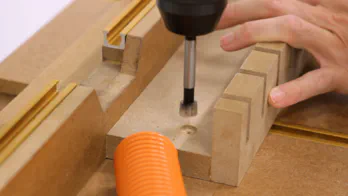 A drill press is used to make counter-sunk holes in the back of the rack.