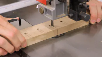 A bandsaw is used to cut slots in a piece of MDF.