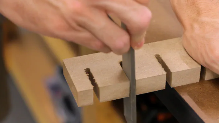A file is used to clean the edge of a slot in MDF.