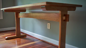A trestle desk made of cherry wood with maple wedges