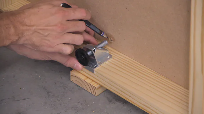 A pencil is used to point to an access hole in an MDF shelf.