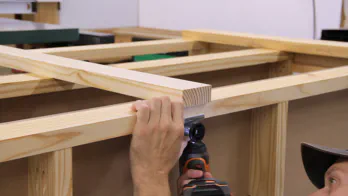 A drill is used to attach an adjustable foot to the workbench.