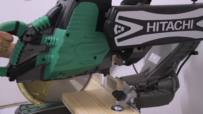 A 12 inch miter saw cutting a board.