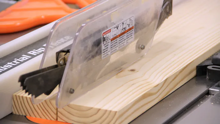 A table saw is used to rip a piece of lumber to width.