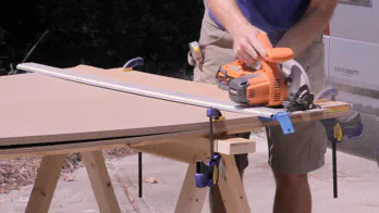A circular saw is used to cut two pieces of MDF at once.