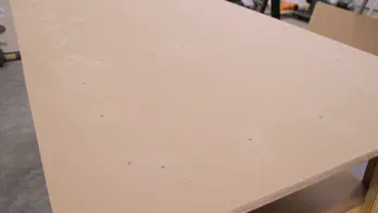 A piece of MDF is screwed to a table top.