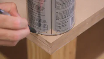 A quart paint can is used to mark a curve on a table top corner.