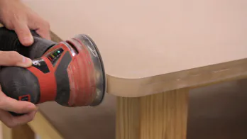 A sander is used to smooth out the table top corner.