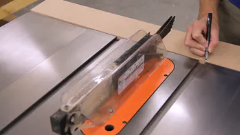 A pencil is used to mark the location of miter tracks from a table saw onto a piece of MDF.