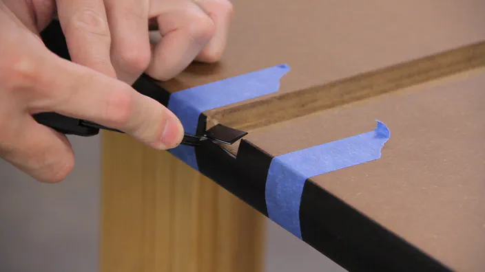 A knife is used to cut a notch in a piece of T-molding.