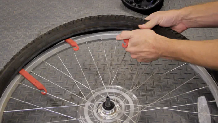 Using multiple tire levers to remove a tire from a bicycle wheel.