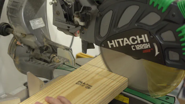 A miter saw is used to cut a board.