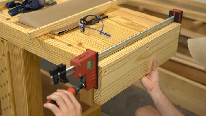 A clamp holds one jaw in place at the bench.