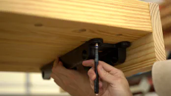 The screw location is marked on the bottom of the bench top.