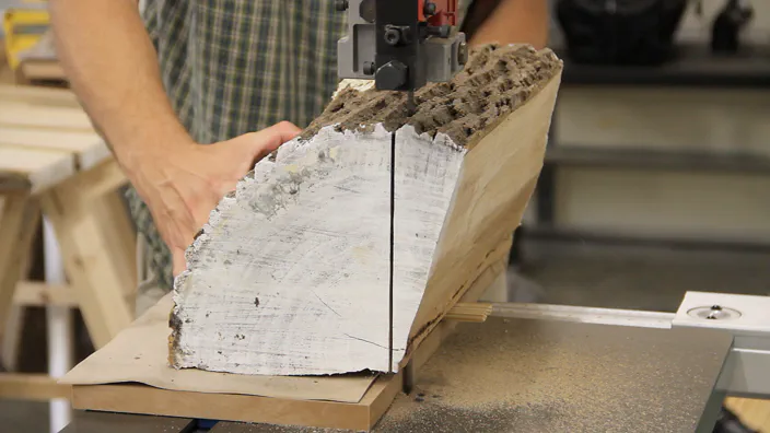 A log being cut on a bandsaw.