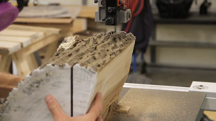 A bandsaw is used to cut a log.