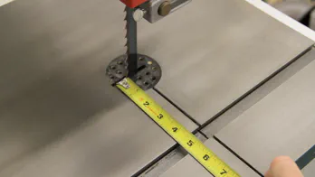 A tape measure is used to measure the distance on a bandsaw.
