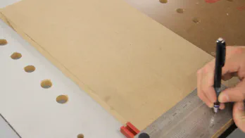 A pencil and square are used to mark a line down a piece of MDF.