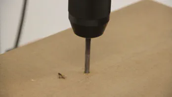 A drill press is used to drill a hole in MDF.