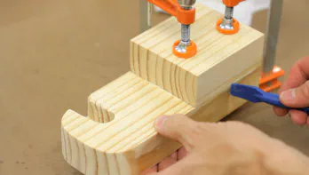 Two pieces of wood are glued and clamped.
